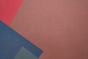 Fototapeta premium Three sheets of colored paper on a brown background. Red, green, blue. Minimalistic composition. Background for text or design. Empty right side. Top view