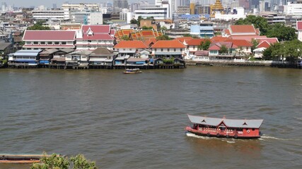 Fototapeta na wymiar Oriental boat floating on river in Krungthep city. Modern transport vessel floating on calm Chao Praya river on sunny day in Bangkok near chinatown. Panorama
