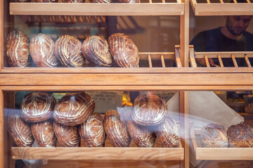 Freshly baked bread loaves on display in a bakery at Broadway market, London with an unrecognised staff in the background