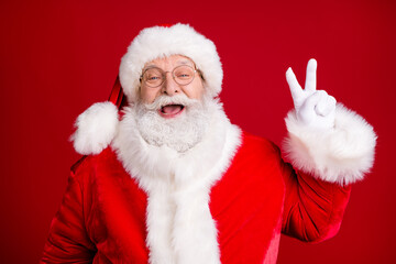 Portrait of crazy stylish santa claus enjoy x-mas christmas make v-sign wear red costume cap white gloves isolated over bright shine color background