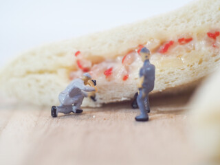 Miniature people team checks the quality of sandwich bread on white background