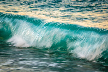 close-up of a turquoise blue wave crashing with motion blur.