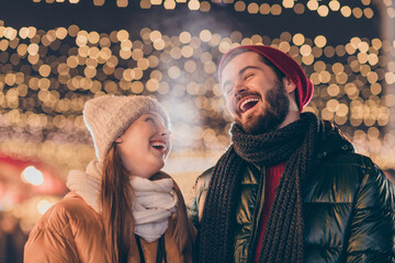Positive couple woman man enjoy x-mas jolly event blow air mouth cold weather having fun under illumination evening outside