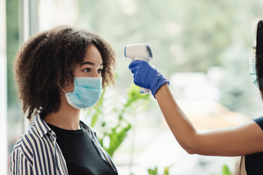 African american woman getting body temperature check at beauty salon, side view