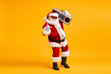 Full size photo of grey white hair bearded santa claus show horned symbol hold boom box on x-mas christmas party wear headwear cap isolated bright shine color background © deagreez