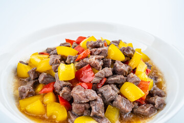 Diced beef with bell pepper on a dish of home cooking on white background