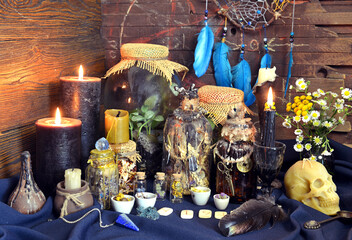Still life with magic bottles with potions and herbs, runes, black candles and skull on witch table.  Esoteric, gothic and occult background, Halloween mystic concept