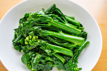 A dish of Chinese vegetable stir-fried Chinese kale and cabbage heart on a wooden table
