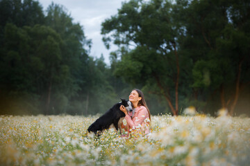 Girl and dog on a field of daisies. Relationship, friendship with a pet