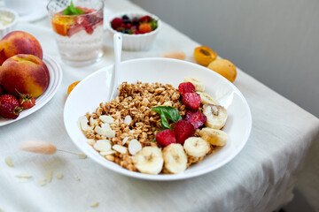 Healthy breakfast bowl, fresh granola, muesli with berries strawberry, banana on white table, Top view, Copy space. Clean eating, detox, dieting, vegetarian food concept