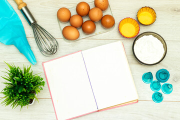Open blank recipe book, eggs and flour  on wood table