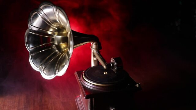 Music concept. Old gramophone on a dark background. Retro gramophone with disc on wooden table with toned backlight. Slider shot