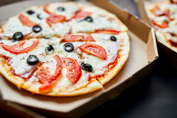 Open box with hot tasty italian sliced pizza on black background, delicious fast food, delivery concept, top view, copy space, flat lay.