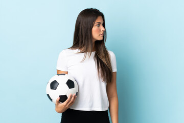 Young football player brazilian girl isolated on blue background looking to the side