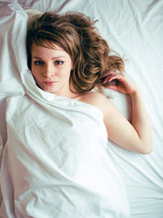 Fototapeta premium pretty blond woman laying in bed on white shits, sexy look romantic