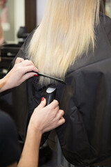 The hairdresser cuts the hair of a blonde woman.