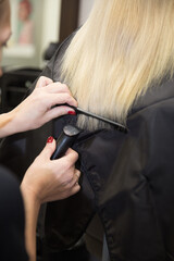 Naklejka premium The hairdresser cuts the hair of a blonde woman.