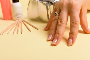 The procedure for removing varnish from nails hybrid nails in progress. Gel nail polish remover foils on woman's hands.