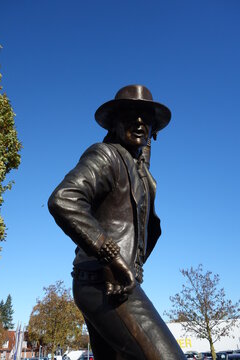 Eine bronzene Statue mit Cowboyhut und Sonnenbrille. Mit dem Sakko nach Monaco Udo Lindenberg Statue in Gronau, Deutschland. Famous german singer statur in action Checker Udo.