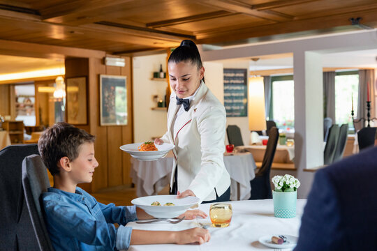 Elegant waitress serving food to boy