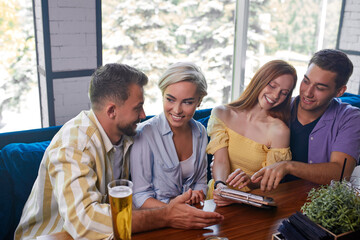 let's order this one, group of friends with menu in cafe, discuss sitting at table, going to have meal