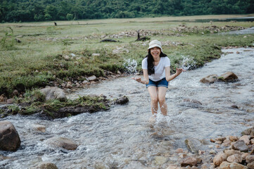 Asian young woman having enjoy and relaxing with nature, field of water stream, waterfall outdoor