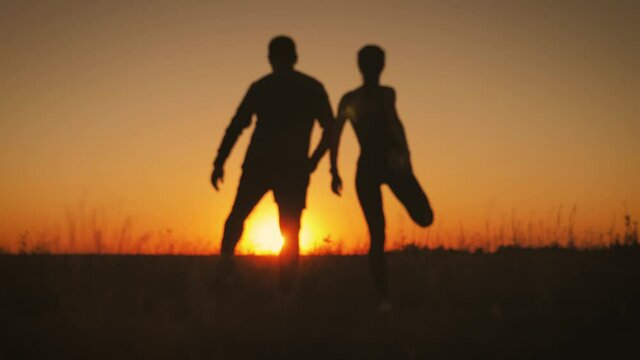 Blur effect, silhouette couple running at sunset. Outdoor sports.