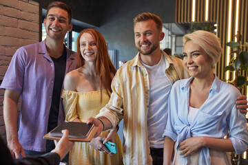 here you are. pleasant blissful group of friends getting the menu in cafe, they are served by a...