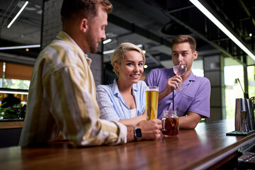 Fototapeta premium beautiful caucasian men and women hold friendly meeting in cafe, they have a great time after work, have talk. leisure, drinks, people and communication concept