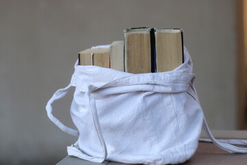 Canvas tote bag filled with old books. Selective focus.