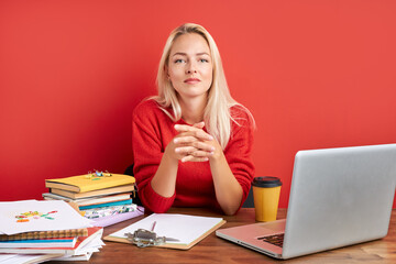 portrait of young caucasian blonde female at work place, she sits in casual wear at office desk,...