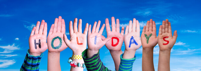 Children Hands Building Colorful English Word Holidays. Blue Sky As Background