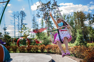 Girl wearing facial mask having fun at amusement park, new reality, summer outdoor