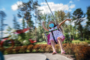 Girl wearing facial mask having fun at amusement park, new reality, summer outdoor