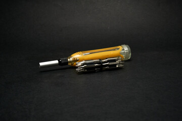 Screwdriver with a universal set of bits, on a dark background.