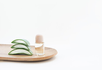 Essence bottle and aloe vera leaves on a white background.