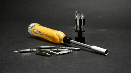 Screwdriver with a universal set of bits, on a dark background.