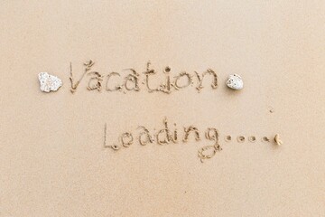 Vacation loading writing on the sand, message on the sand background, outdoor day light