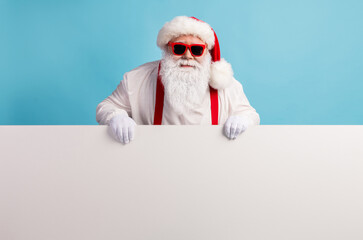 Naklejka premium Portrait of his he nice attractive funky cheery confident white-haired Santa holding in hands demonstrating copy space board advert ad isolated over bright vivid shine vibrant blue color background