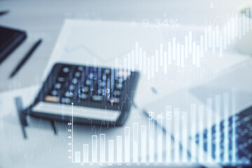 Abstract virtual financial graph hologram on calculator and laptop background, forex and investment...