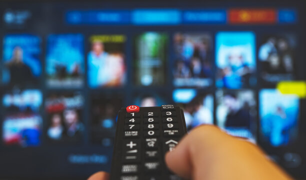 Male hand with remote control pointing on Smart TV.