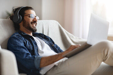 Indian Freelancer Man Working On Laptop Online At Home And Listening Music