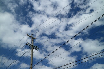 青空と白い雲を背景に撮影した電柱と電線