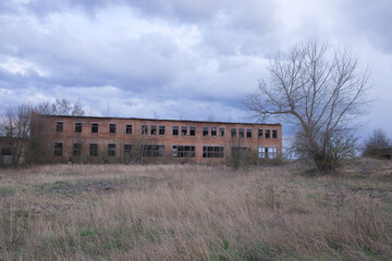 An abandoned two-story brick building. Cloudy evening landscape. Cloudy sky.