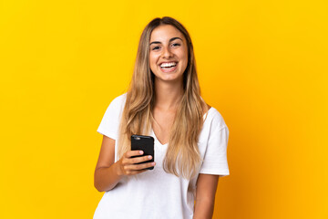 Young hispanic woman over isolated yellow background using mobile phone