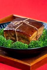 Dong Po Rou (Dongpo pork meat) in a beautiful blue plate with green broccoli vegetable, traditional festive food for Chinese new year cuisine meal, close up.
