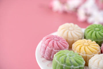 Colorful snow skin moon cake, sweet snowy mooncake, traditional savory dessert for Mid-Autumn Festival on pastel pale pink background, close up, lifestyle.