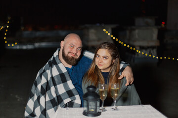 Lovers on the roof sit at a table with champagne.