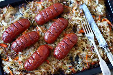 Selective focus. Bavarian sausages with sauerkraut on a pan. Beer and pretzels. Oktoberfest food tray.