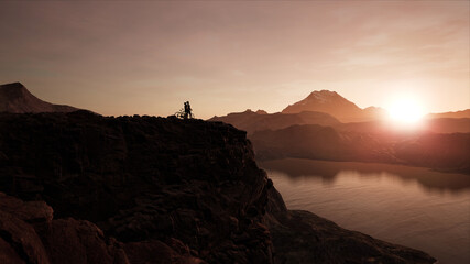 WIDE Male and female cyclists enjoying sunset on a cliff near lake during bicycle ride